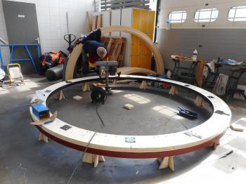 The first two elements of the dome being bolted together, the rafters are in the background.